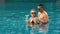 The loving couple hugs and kisses, drinking blue cocktail alcohol liquor in swimming pool at hotel outdoor. Portrait of