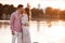 Loving couple kissing on the lake at sunset. Beautiful young couple in love walking on the shore of the lake at sunset in the rays