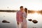 Loving couple kissing on the lake at sunset. Beautiful young couple in love walking on the shore of the lake at sunset in the rays