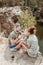 Loving couple listening to music in earphones while sitting on cliff near lake