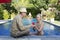 Loving couple in the pool in a garden with tropical trees. The man embraces the woman