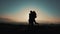 A loving couple runs to meet each other in embrace, man twists his woman against the sunset on the mountains. Slow