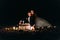 Loving couple share a romantic dinner with candles and cake at beach, coast against wonderful night