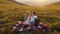 Loving couple sitting on a mountain meadow and enjoys the view of the sunset