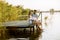 Loving couple sitting on the pier on lake