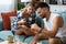 Loving couple sitting on sofa at home. Man and woman relaxing on couch with smartphone in living room. Young people relaxing in