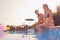 Loving Couple On Summer Vacation Sitting On Edge Of Swimming Pool