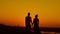 Loving couple at sunset - young man and beautiful girl stands at summer meadow and looking to sun, silhouette