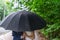 Loving couple take shelter together beneath an umbrella in the rain.