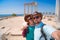 A loving couple of travelers takes a selfie with a view of the ruins of the ancient Roman temple of Apollo. Sunglasses Side,