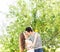 Loving couple under blossoming branches spring day. Young adult brunette man and woman kissing in fresh blossom apple