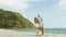 Loving couple in white dress, sunglasses, relax in hugging and kissing. Woman and man walk in beach.