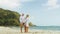 Loving couple in white dress, sunglasses, relax in hugging and kissing. Woman and man walk in beach.