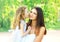 Loving daughter kissing mother, happy young mom and child in warm sunny summer day on the nature