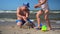 Loving father and daughter girl playing together with sand at coast of sea