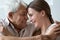 Loving grandfather touch foreheads of adult granddaughter relative people hugging