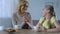 Loving grandma drinking tea with cute granddaughter, holding her hand, family