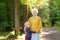 Loving grandson tenderly embracing his joyful elderly grandmother during walking at summer park