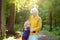 Loving grandson tenderly embracing his joyful elderly grandmother during walking at summer park