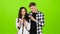Loving guy and girl look in the phone and choose common pictures. Green screen