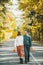 Loving happy couple in autumn in park walking on asphalt road and holding autumn maple leaves in hands