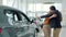 Loving husband giving car to beloved wife as a surprise in motor showroom