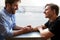 Loving Male Gay Couple Sitting At Table In Coffee Shop Holding Hands