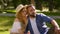 Loving man and woman enjoying picnic in summer park, talking together, sitting on green grass and looking aside