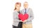 Loving middle aged couple holding a red heart and looking at cam