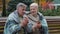 Loving middle-aged couple pensioners man woman grandparents rest together sit on bench outdoors drinking hot coffee