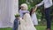 Loving Middle Eastern little son giving wedding bouquet to beautiful mother getting married outdoors. Side view of happy