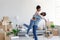 Loving millennial black husband lifting excited wife, celebrating moving day, have fun in modern room