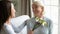 Loving millennial girl greeting senior mom presenting flowers