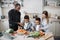 Loving mom, dad and small sons kids cooking dinner together.