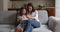 Loving mom read book her little daughter seated on sofa