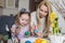 Loving mother and her daughter painting easter eggs