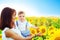 Loving mother holding son in her arms in rest on sunflowers field. Nature and summer