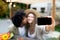 Loving multiracial couple kissing and taking selfie near RV on camping trip in autumn, mockup for app or website