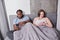 Loving multiracial couple sitting at the bed at the morning and ignoring each other