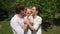 Loving parents embracing and kissing cute boy in summer garden. Handheld shot