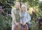 Loving retired spouses embracing, resting in garden in countryside, standing near wicker chair and smiling at camera