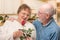 Loving Senior Adult Man Giving Red Rose to His Wife In a Kitchen