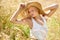 Loving the sunshine. Gorgeous young woman wearing a straw hat and stretching in a field.