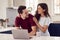 Loving Transgender Couple At Home Together Looking At Laptop On Kitchen Counter