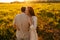 Loving unrecognizable young man and redhead woman in love hugging, touching, stroking standing on field with green grass