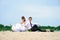 Loving wedding couple sitting near water and strew sands