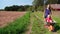 Loving woman pushing wheelbarrow with happy little girl through village way