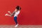 Loving young couple stands on Valentine`s Day against the backdrop of a red wall and having fun, a strong man lifted a woman in