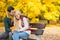 Loving young man hugging shy woman on park bench during autumn