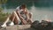 Loving young teenager couple embraces while relaxing at campsite on forest rivershore